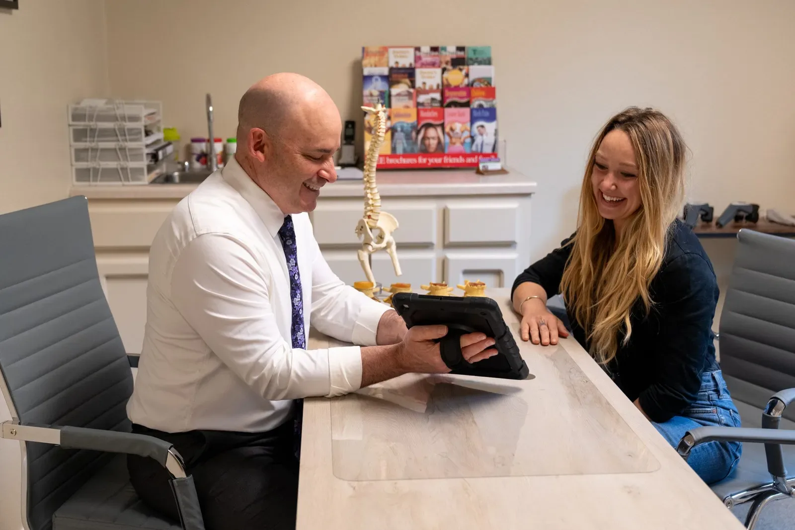 Chiropractor and smiling patient reviewing spine model together
